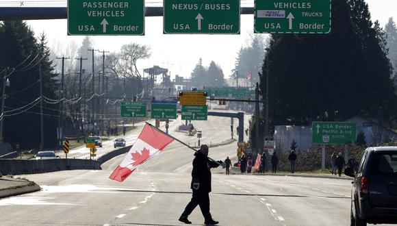 Un manifestante sostiene una bandera nacional canadiense mientras los manifestantes anti vacuna se reúnen en la autopista 15 cerca del cruce fronterizo entre Estados Unidos y Canadá. (Foto: Jason Redmond / AFP)