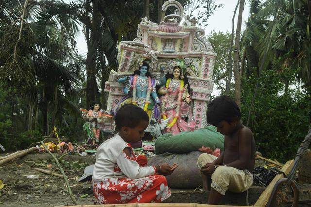 Los niños juegan cerca de un ídolo hindú dañado después de la llegada del ciclón Amphan en el área de Khejuri de East Midnapore, Bengala Occidental, India, el 21 de mayo de 2020. (AFP / Dibyangshu SARKAR)