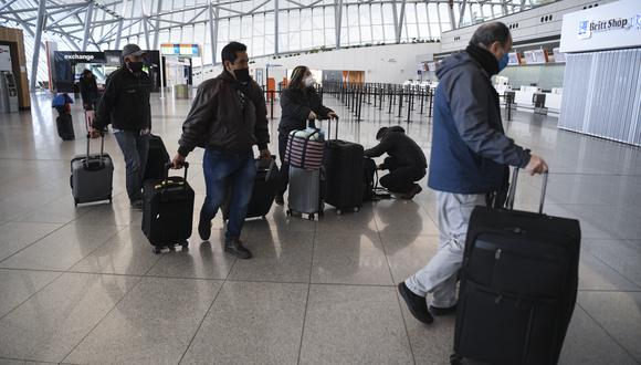 Los pasajeros varados caminan con su equipaje en la sala de facturación del Aeropuerto Internacional de Carrasco en Ciudad de la Costa, departamento de Canelones, cerca de la capital uruguaya, Montevideo, el 2 de julio de 2020. (Foto de Eitan ABRAMOVICH / AFP)