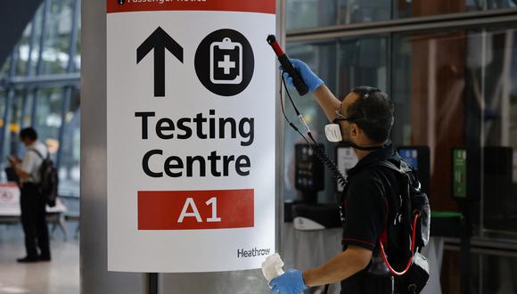Un miembro del personal limpia la señalización en la Terminal 5 de Heathrow en el oeste de Londres el 2 de agosto de 2021 a medida que disminuyen las restricciones de cuarentena. (Foto: Tolga Akmen / AFP)