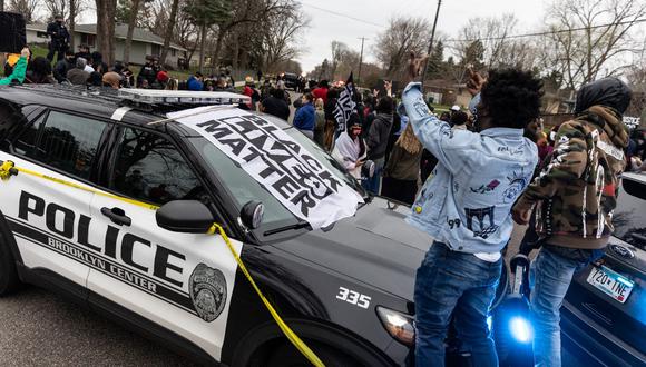 Los manifestantes se paran en la parte superior de un automóvil de la policía después de que un oficial disparó y mató a un afroamericano en Minneapolis. (Kerem Yucel / AFP)