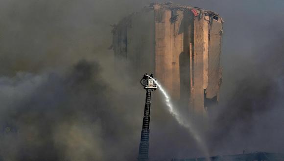 Los bomberos libaneses se paran en una escalera en medio de una nube de humo en el puerto de Beirut. (AFP / ANWAR AMRO).