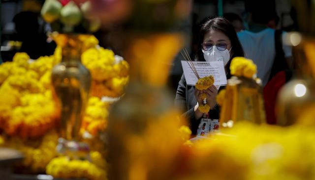Una mujer que lleva una máscara de protección ofrece sus oraciones a Brahma, el Dios hindú de la creación, en el Santuario de Erawan en Bangkok. (EFE).
