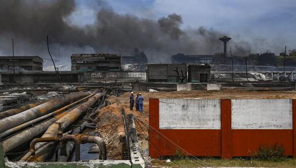 Empleados de la estatal petrolera Cupet inspeccionan los daños en el depósito de combustible que estuvo envuelto en llamas durante cinco días luego de que un rayo impactara en uno de sus tanques, en Matanzas, Cuba, el 10 de agosto de 2022. (Foto de Yamil LAGE / AFP)