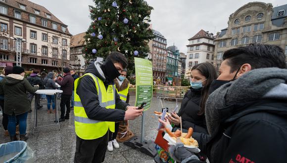Un empleado municipal controla el pase sanitario de los visitantes para permitirles ingresar a un área de alimentos, en Estrasburgo, este de Francia, el 1 de diciembre de 2021. (Foto: PATRICK HERTZOG / AFP)