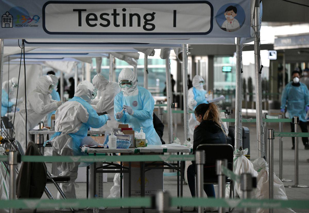Personal médico toma muestras para diagnosticar coronavirus de un pasajero extranjero en una cabina de pruebas fuera de un aeropuerto internacional. (Foto: AFP/Jung Yeon-je)