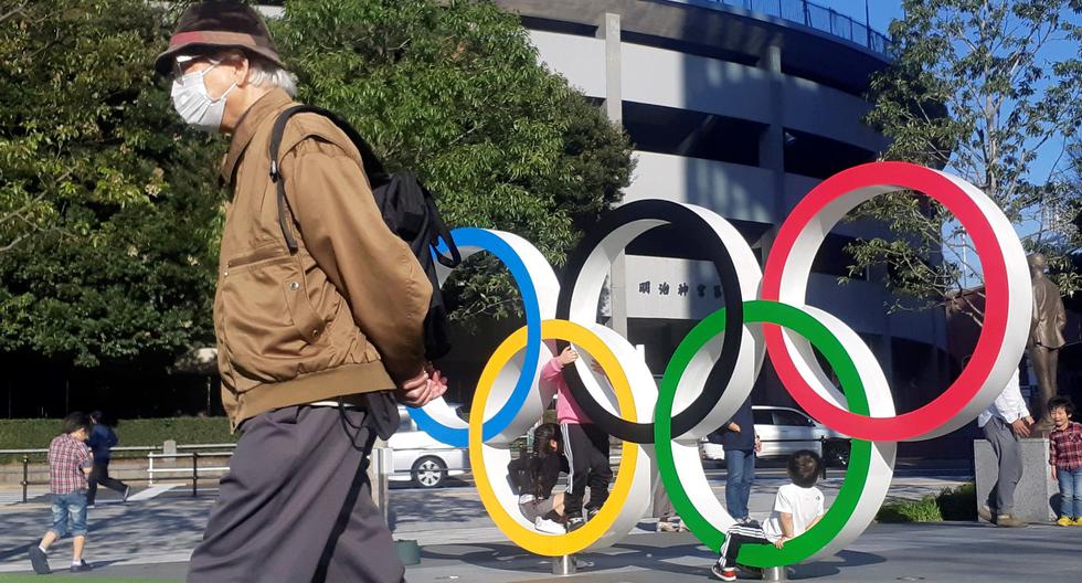 Un hombre protegido por una máscara para evitar posibles contagios da la espalda a los anillos olímpicos instalados en Tokio. (EFE/Demófilo Peláez).