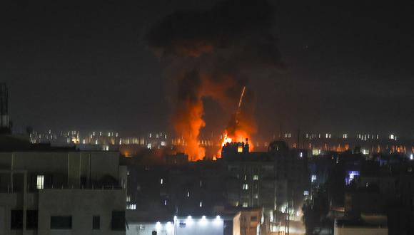 Las explosiones iluminan el cielo nocturno sobre los edificios en la ciudad de Gaza mientras las fuerzas israelíes bombardean el enclave palestino. (Foto de MAHMUD HAMS / AFP)