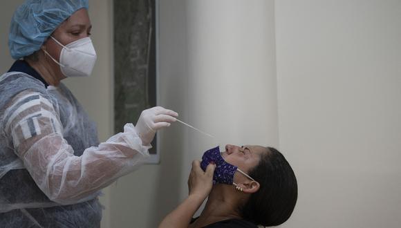 Un trabajador de la salud toma una muestra de una mujer para detectar la enfermedad del nuevo coronavirus COVID-19 en la unidad de salud pública Manoel Jose Ferreira en Río de Janeiro, Brasil. (Foto: MAURO PIMENTEL / AFP)