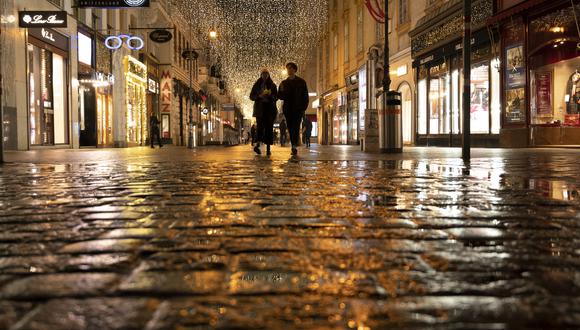 Una pareja pasa frente a tiendas boutique cerradas en Graben, una calle en el centro de la ciudad de Viena que normalmente está abarrotada de gente el 22 de noviembre de 2021. (Foto de JOE KLAMAR / AFP)