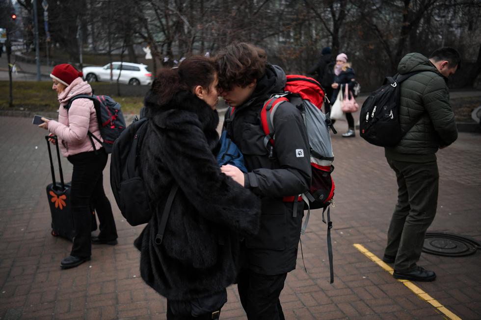 Una pareja se abraza cuando una mujer con una maleta pasa frente a una estación de metro en Kiev en la mañana del 24 de febrero de 2022. (Foto: Daniel LEAL / AFP)