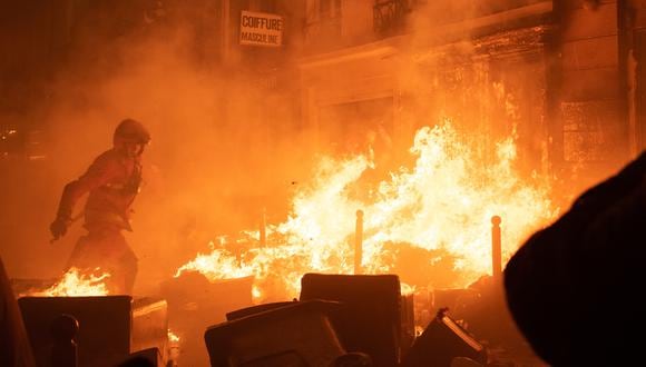 Un bombero intenta extinguir un incendio durante una manifestación, una semana después de que el gobierno impulsara una reforma de las pensiones en el parlamento sin votación, utilizando el artículo 49.3 de la constitución, en París el 23 de marzo de 2023. (Foto de Anna KURTH / AFP)