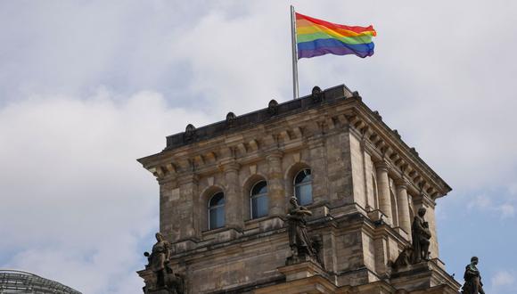 La bandera del arco iris se iza en el techo del Reichstag, el edificio que alberga la Cámara Baja del Parlamento alemán, por primera vez antes de la manifestación número 44 del Día de Christopher Street (CSD) durante el mes del Orgullo en Berlín el 23 de julio de 2022. (Foto por DAVID GANNON / AFP)