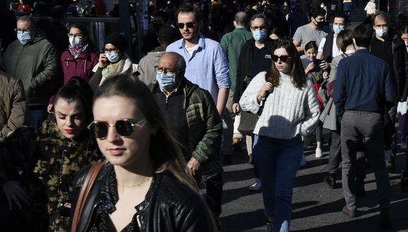 Personas, algunas con mascarillas, caminan por una calle mientras disfrutan de un día en Barcelona el 31 de diciembre de 2021. (Foto de Pau BARRENA / AFP)