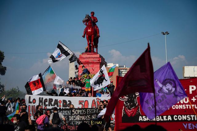 La gente protesta frente al monumento al General Baquedano -pintado de rojo- contra el gobierno del presidente de Chile, Sebastián Piñera, en la Plaza Italia. (AFP/Martin BERNETTI).