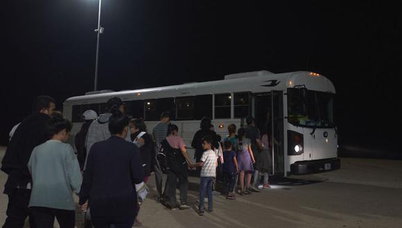 Agentes de la Patrulla Fronteriza de EE. UU. dirigen a los migrantes a un autobús para su procesamiento después de cruzar ilegalmente la frontera entre EE. UU. y México en Yuma, Arizona, temprano en la mañana del 11 de julio de 2022. (Foto de allison cena / AFP)