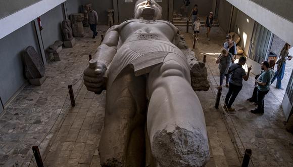 Los turistas contemplan la colosal estatua reclinada de piedra caliza (de 10 metros de largo) del antiguo faraón egipcio Ramsés II (1279-1213 a. C.). (Foto de Amir MAKAR / AFP)