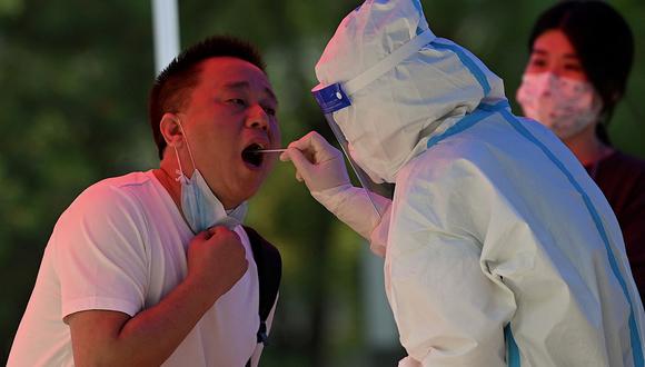 Un trabajador de la salud (derecha) toma una muestra de hisopo de un hombre para analizarlo por el Covid-19 en un sitio de recolección de hisopos en Beijing el 20 de junio de 2022. (Foto de Noel Celis / AFP)