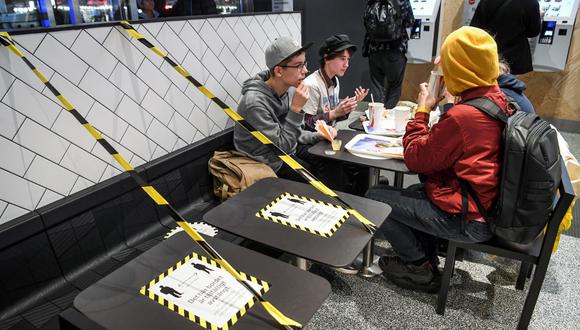 Los invitados disfrutan de su comida en un restaurante de comida rápida junto a mesas grabadas en el centro de Estocolmo el 12 de noviembre de 2020, en medio de la pandemia del nuevo coronavirus. (Fredrik SANDBERG / Agencia de noticias TT / AFP)