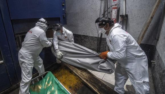 Personal cargando un cadáver, víctima de coronavirus. (Foto: Pedro PARDO / AFP).