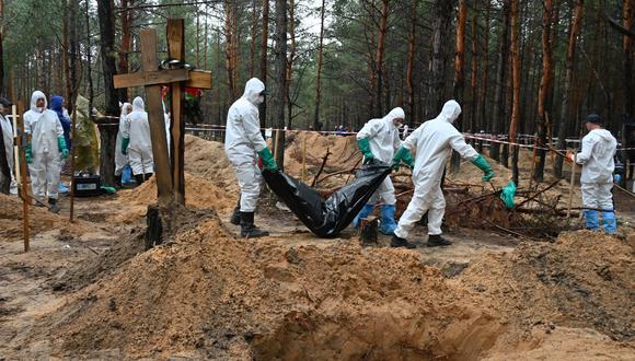Los investigadores se llevan una bolsa para cadáveres en un bosque cerca de Izyum, en el este de Ucrania, el 23 de septiembre de 2022. (Foto: SERGEY BOBOK / AFP)