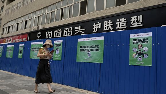 Una mujer pasa frente a un área residencial cercada bajo encierro debido a las restricciones del coronavirus en Beijing el 20 de junio de 2022. (Foto de Noel Celis / AFP)