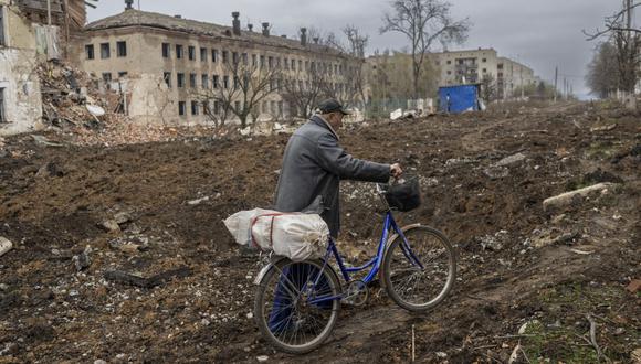 Un hombre camina con su bicicleta en la calle de Siversk, una ciudad en el este de Ucrania golpeada por las fuerzas rusas hace un par de días, el 11 de noviembre de 2022, en medio de la invasión rusa de Ucrania. (Foto de BULENT KILIC / AFP)