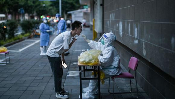 Un trabajador de la salud toma una muestra de hisopo de un hombre para detectar el coronavirus Covid-19 en el distrito de Jing'an de Shanghái el 5 de julio de 2022. (Foto de Hector RETAMAL / AFP)