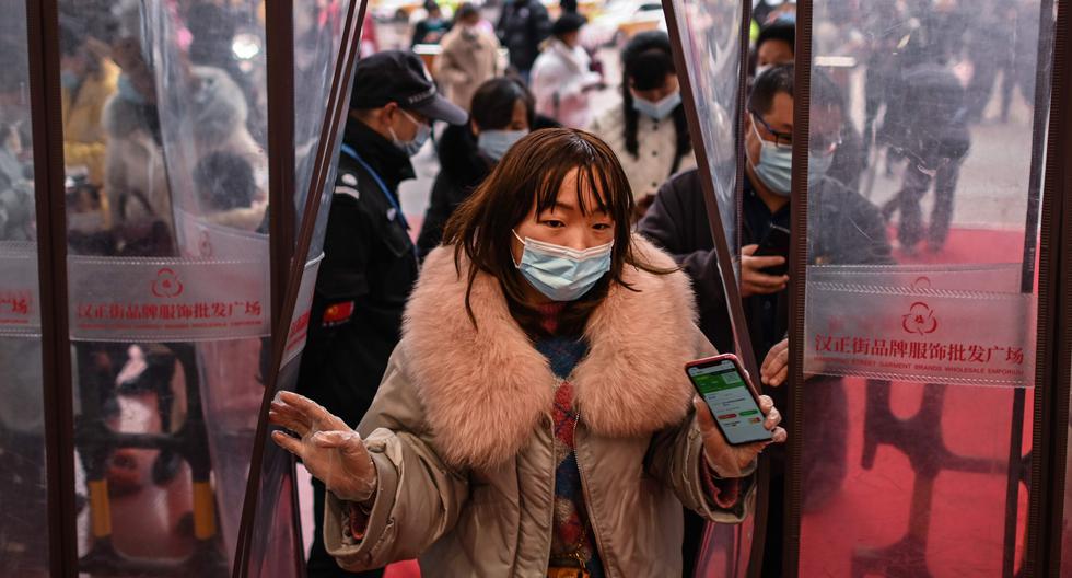 Una mujer que usa una mascarilla como medida preventiva contra el coronavirus ingresa a un centro comercial después de mostrar su código de salud en Wuhan, provincia central de Hubei en China. (Foto: HÉCTOR RETAMAL / AFP)