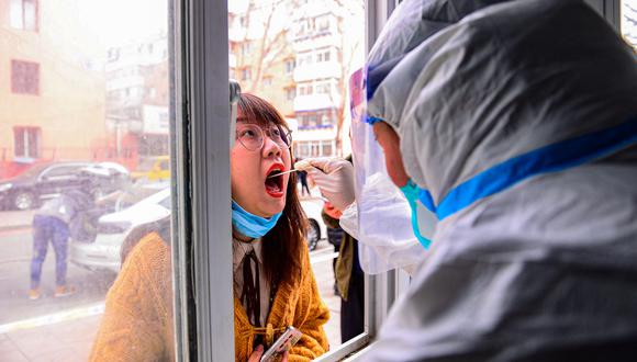 Un residente (izquierda) se somete a una prueba de ácido nucleico para el coronavirus Covid-19 en Shenyang, en la provincia nororiental china de Liaoning. (Foto: AFP)