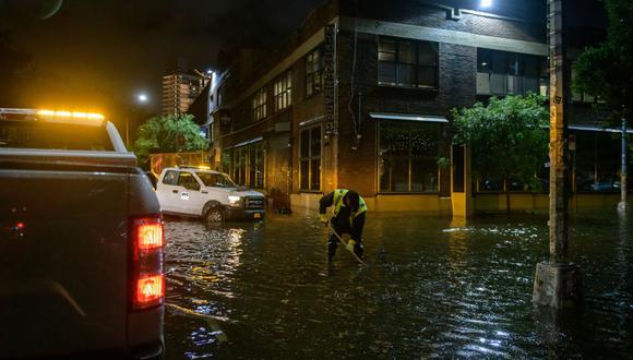 Un trabajador desbloquea los desagües en una calle afectada por las inundaciones en Brooklyn, Nueva York, a principios del 2 de setiembre de 2021. (Ed JONES / AFP).