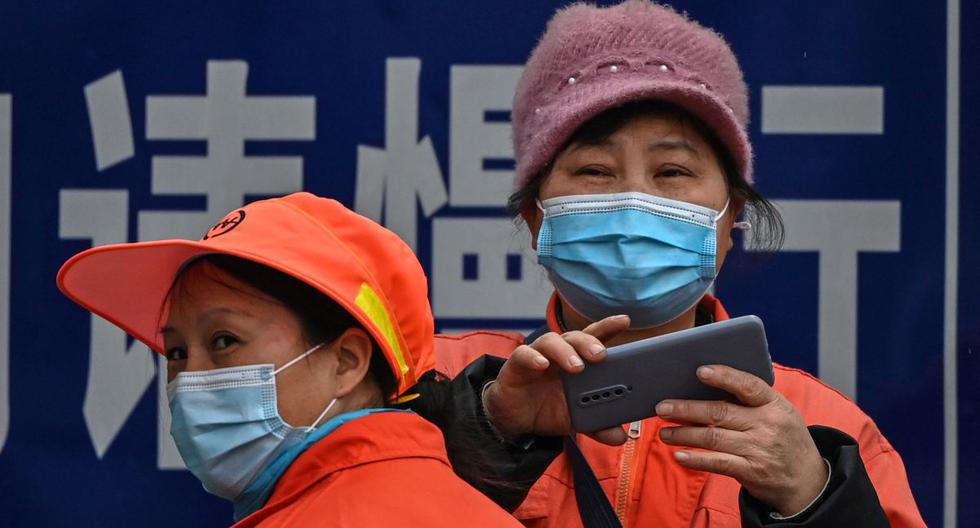 Una mujer usa su teléfono frente al centro comunitario de Jiangxinyuan, donde miembros del equipo de la Organización Mundial de la Salud (OMS) que investigan los orígenes del coronavirus COVID-19 están de visita en Wuhan. (Foto de Hector RETAMAL / AFP).