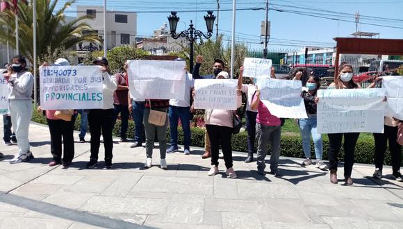 Padres de familia con carteles en exteriores de la municipalidad de Arequipa.