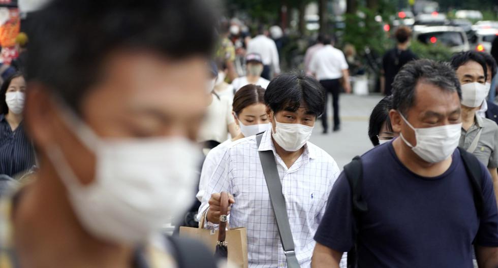 Los peatones que llevan mascarillas por el coronavirus caminan este miércoles en una calle del distrito de Shinjuku en Tokio, Japón. (EFE/EPA/FRANCK ROBICHON).