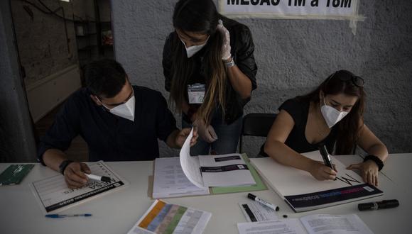 Trabajadores del Servicio Electoral de Chile (Servel) instalan un colegio electoral habilitado para el plebiscito. (Foto de Martin BERNETTI / AFP).