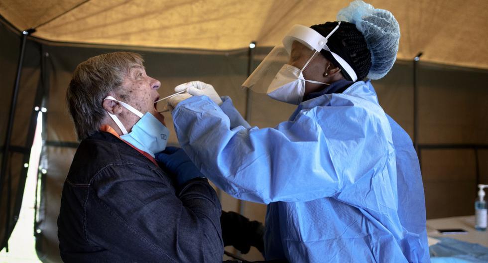 Un hombre, residente de Sophia Town, Johannesburgo (Sudáfrica), abre la boca para recibir un hisopo de prueba para el coronavirus. (Luca Sola / AFP).