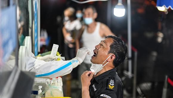Un trabajador de la salud toma una muestra de hisopo a un hombre para analizarla en Beijing el 10 de julio de 2022. (Foto de Hector RETAMAL / AFP)