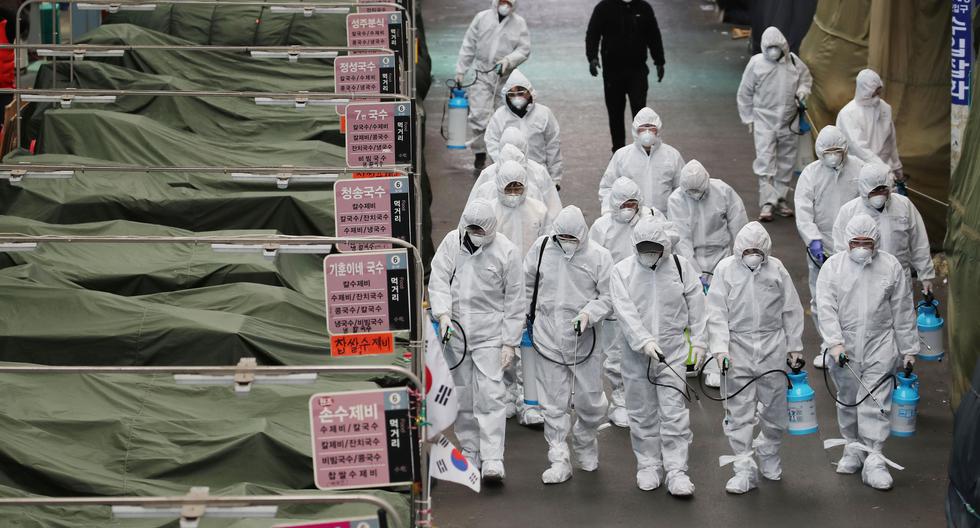 Trabajadores del mercado que usan desinfectante en aerosol de equipo de protección en un mercado en la ciudad de Daegu, en el sureste del país. (AFP).