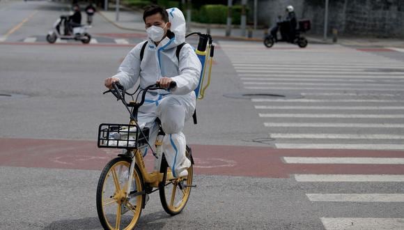 Un hombre con equipo de protección personal  monta una bicicleta por una calle tranquila en Beijing el 9 de mayo de 2022. (Foto: Noel Celis / AFP)