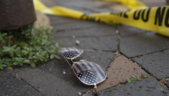 La cinta policial sobre el crimen se ve cerca de unas gafas de sol con el tema de la bandera estadounidense tiradas en el suelo en la escena del tiroteo del desfile del 4 de julio en Highland Park, Illinois, el 4 de julio de 2022. (Foto de Youngrae Kim / AFP)