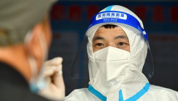 Esta foto tomada el 10 de mayo de 2022 muestra a un trabajador médico tomando una muestra de un hisopo de un residente en Xiayi, en la provincia central china de Henan. (Foto de AFP)