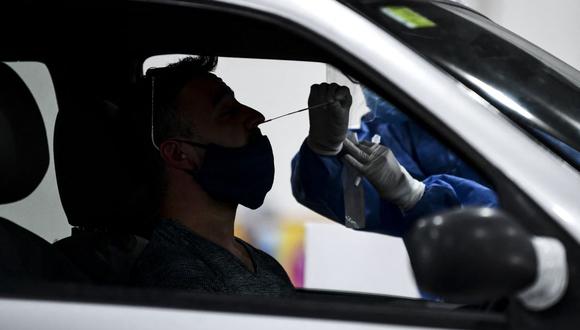 Imagen referencial. Un trabajador de salud recolecta muestras para la prueba de detección de casos de coronavirus dentro de un automóvil, en el centro de convenciones Costa Salguero, en Buenos Aires, el 5 de abril de 2021. (RONALDO SCHEMIDT / AFP).