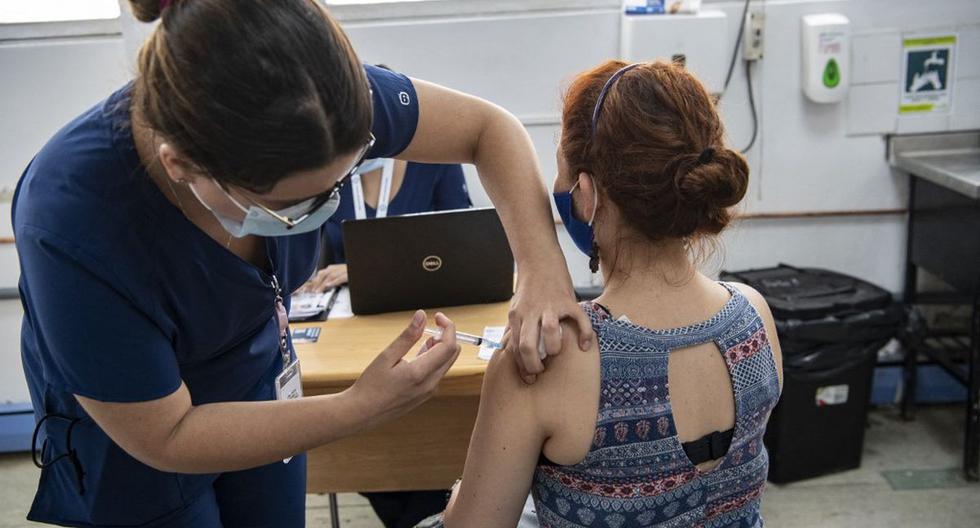 La enfermera chilena María Paz Herreros, de 32 años, quien fue la primera en inocular a un paciente contra el COVID-19 en Chile, inyecta a una mujer una vacuna china, en el Hospital Metropolitano de Santiago, el 26 de febrero de 2021. (Foto de MARTIN BERNETTI / AFP).
