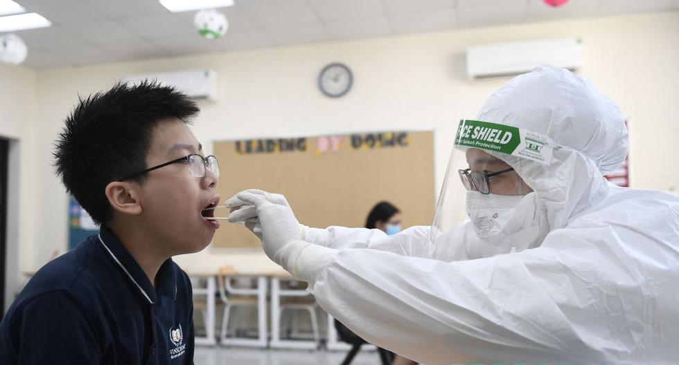 Un trabajador de la salud que usa equipo de protección personal (EPP) realiza una prueba de coronavirus en un estudiante en la escuela privada Vinschool, en Hanoi (Vietnam), el 22 de mayo de 2021. (Nhac NGUYEN / AFP).