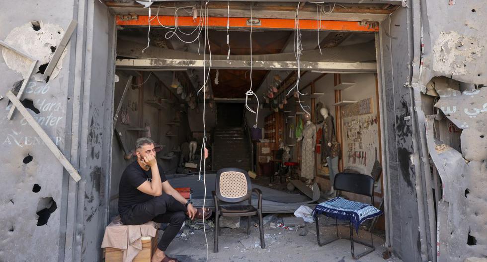 Una persona se sienta a la entrada de su tienda dañada en el distrito comercial de al-Rimal en la ciudad de Gaza, el 22 de mayo de 2021. (Emmanuel DUNAND / AFP).