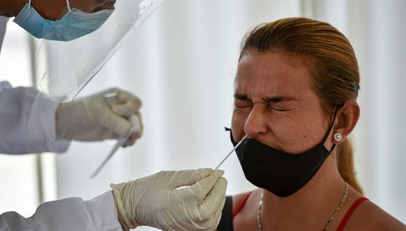 Un trabajador de salud recolecta una muestra de hisopo para una prueba de coronavirus COVID-19 de una mujer en Cali, Colombia, el 21 de enero de 2021, en medio de la nueva pandemia de coronavirus. (Foto de Luis ROBAYO / AFP)