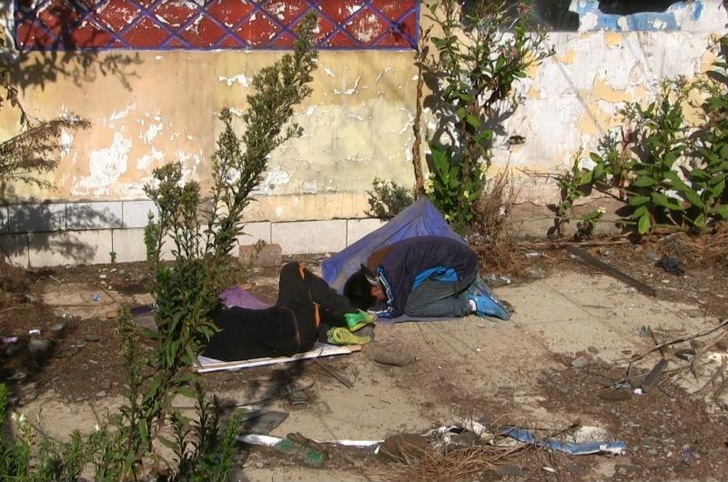 Menores duermen en la calle abrigados con afiche y paraguas 