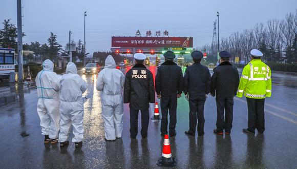 Miembros del personal médico que usan ropa protectora para ayudar a detener la propagación de un virus mortal que comenzó en Wuhan, haciendo guardia con agentes de policía en un punto de control de autopistas en Tengzhou, en la provincia oriental china de Shandong. (Foto: AFP)