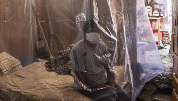 Jonathan, de 30 años, se sienta en su cama detrás de una protección plástica mientras los médicos realizan una ronda de visitas en Ate (Foto: Ernesto Benavides / AFP)