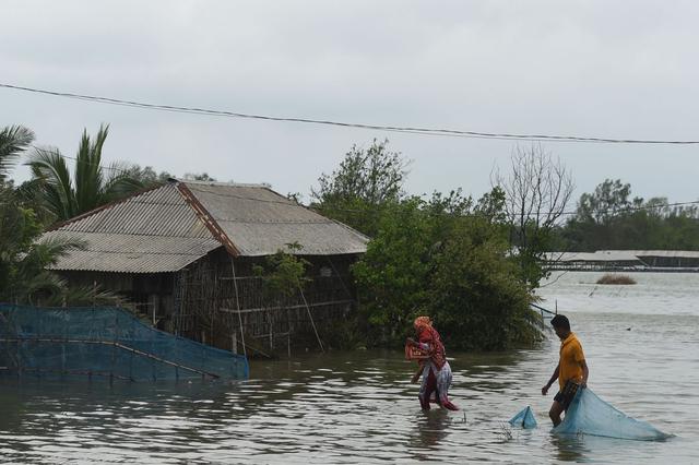 Residentes caminaron por un área inundada después de que una presa se rompió después de la llegada del ciclón Amphan en Shyamnagar, India, el 21 de mayo de 2020. (AFP / Munir Uz zaman)